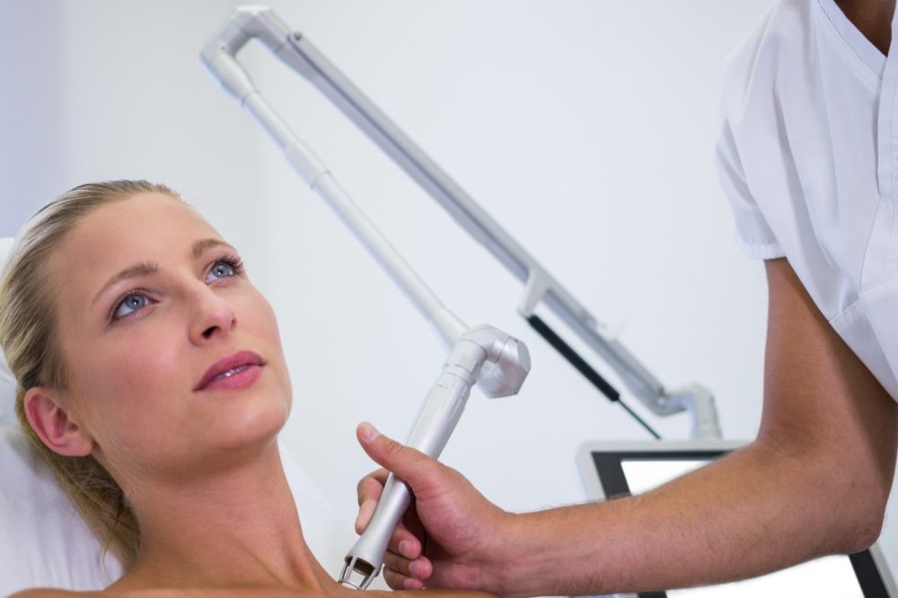 dermatologist-removing-mole-from-womans-shoulder-min dermatologist-removing-mole-from-womans-shoulder-min